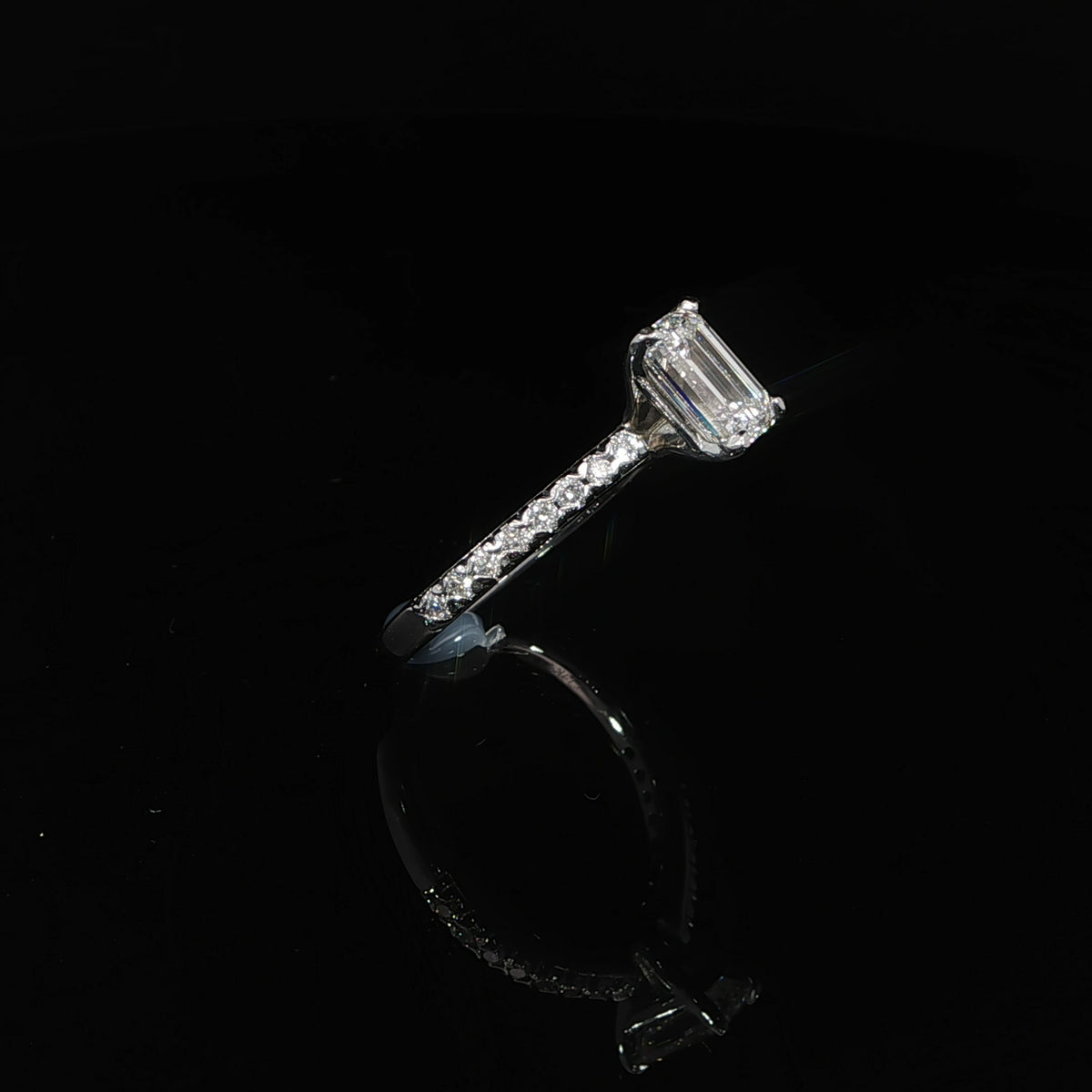 Side angle of a 14K white gold ring with a 1.13-carat emerald-cut center and diamond-set band.