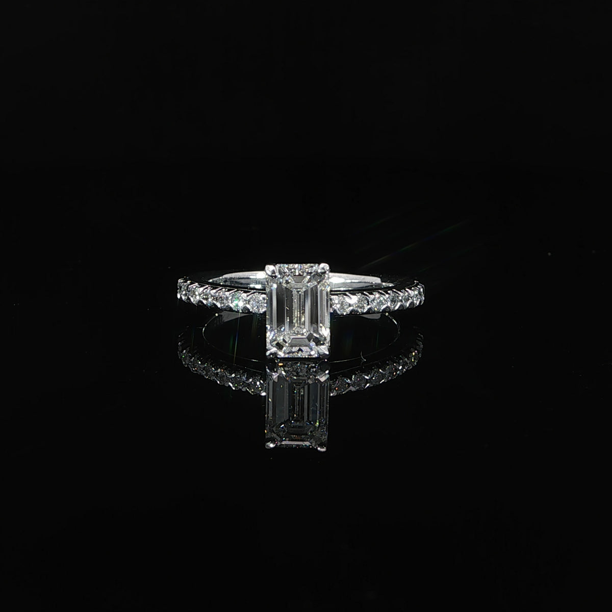 Front view of a 1.13-carat emerald-cut solitaire with round diamonds along its 14K white gold band.