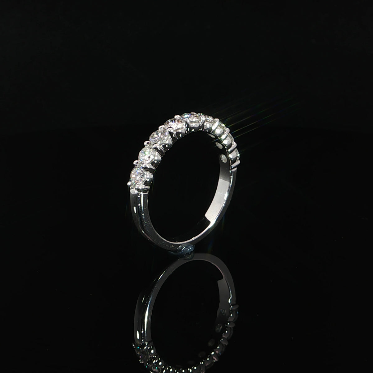 Upright side profile of a half-eternity diamond band showing individual settings and a polished lower shank.