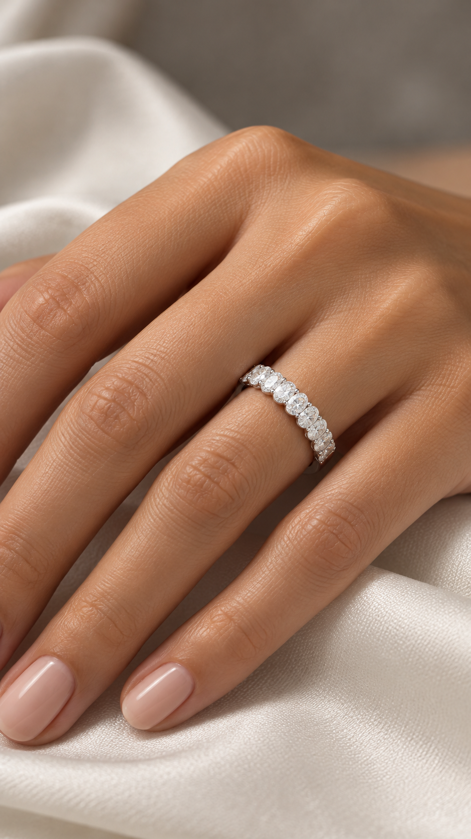 Front detail of a 14K white gold wedding ring with a continuous row of oval diamonds across its upper half.