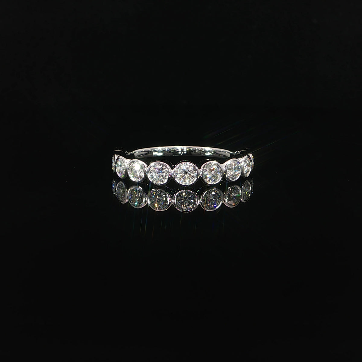 Front view of a 14K white gold band with round lab-grown diamonds individually framed in polished bezels.