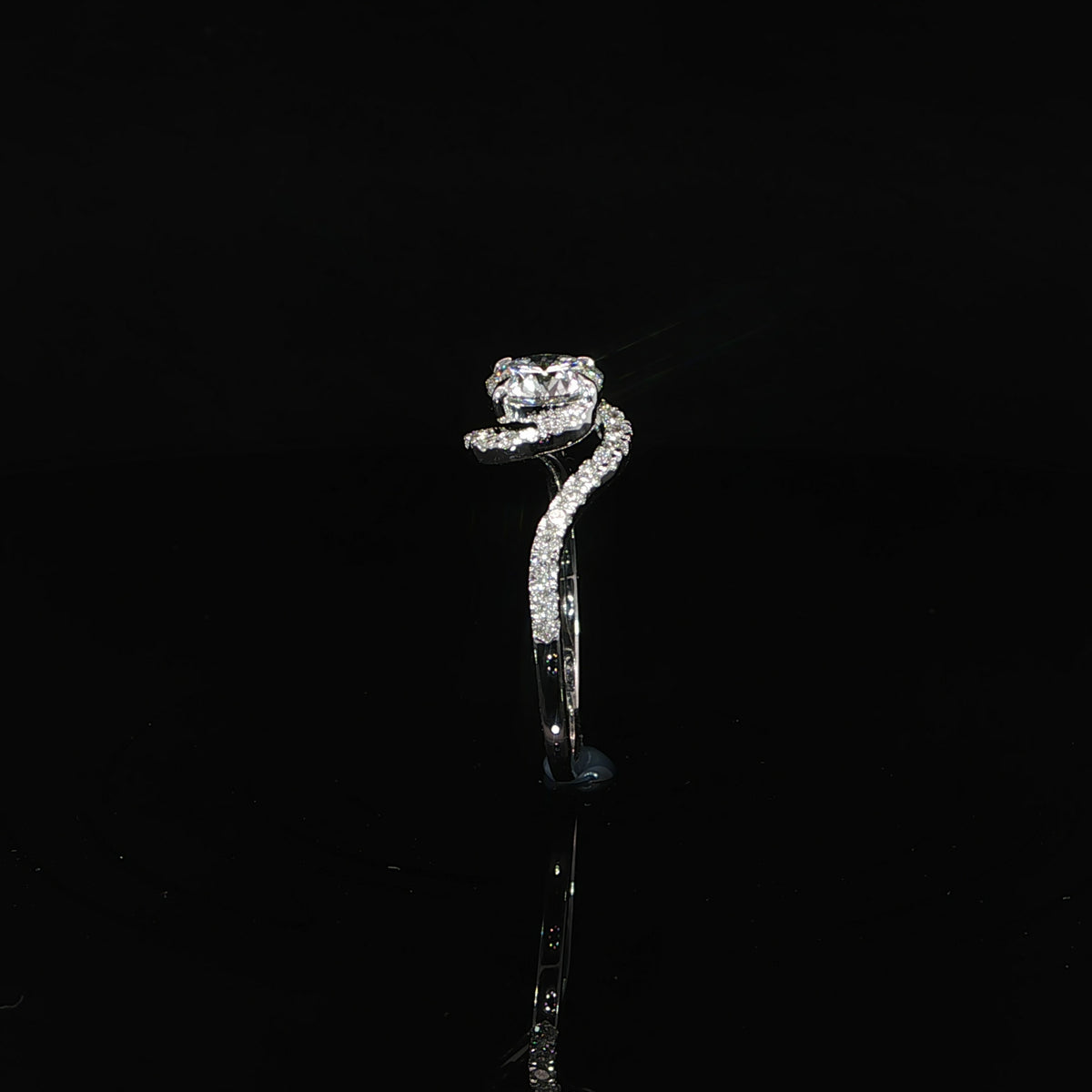 Side profile of a white gold round diamond ring with a raised setting and flowing diamond-accented band.