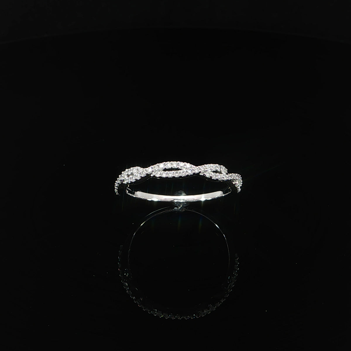 Angled view of a 14K white gold twist band with diamond-set strands and elongated openings.