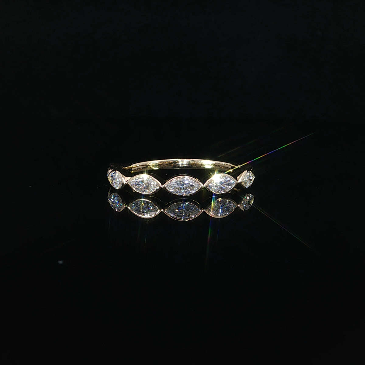 Front view of a 14K yellow gold band with horizontally set marquise diamonds in polished bezel settings.