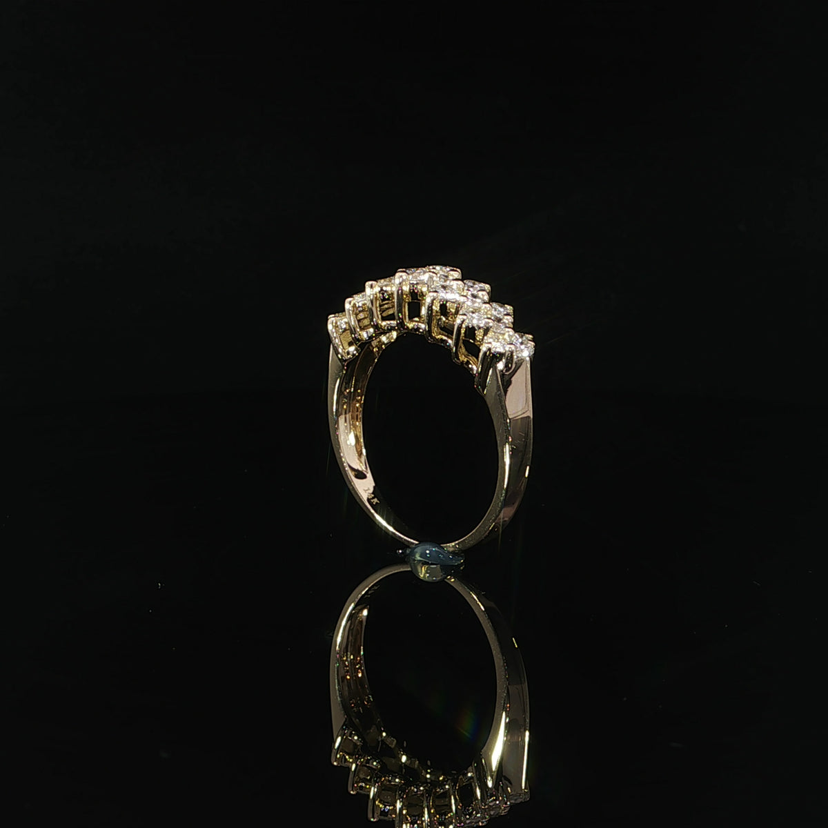 Side profile of a 14K yellow gold diamond anniversary band showing its open gallery and raised settings.