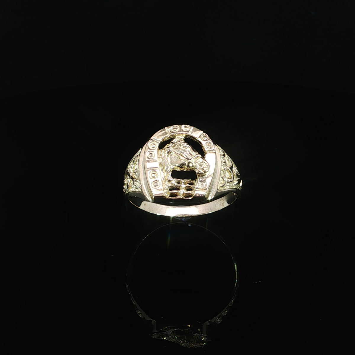 Yellow gold horseshoe ring showing a raised top, textured triangular shoulder and tapered band.