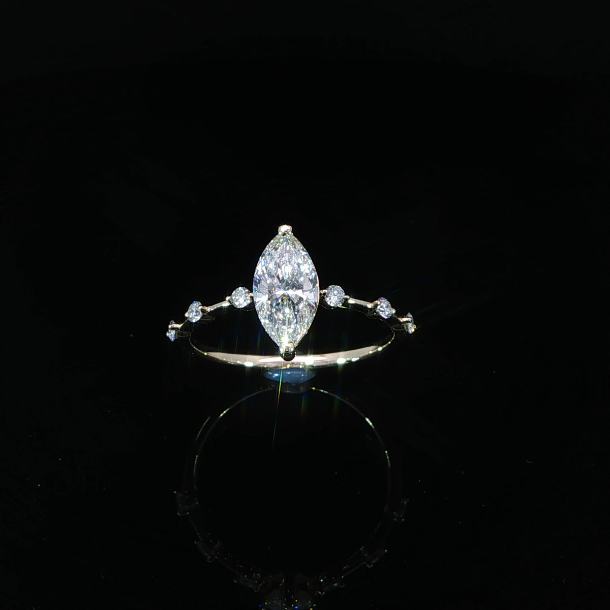 Angled view of a 14K yellow gold engagement ring with a marquise center diamond and station-set side diamonds.