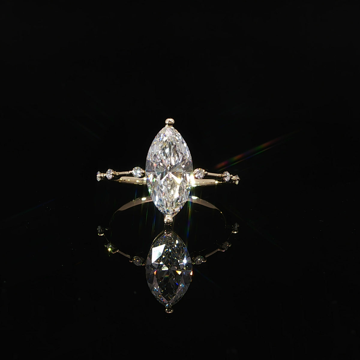 Front view of a 14K yellow gold engagement ring featuring a marquise center diamond and diamond station band.
