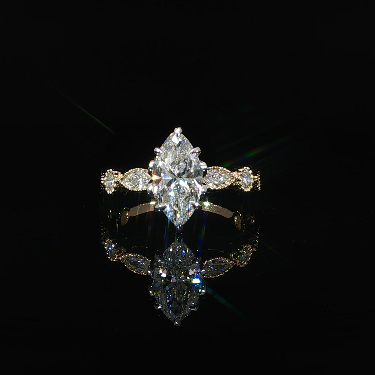 Front view of a yellow gold marquise diamond ring resting on a reflective black surface