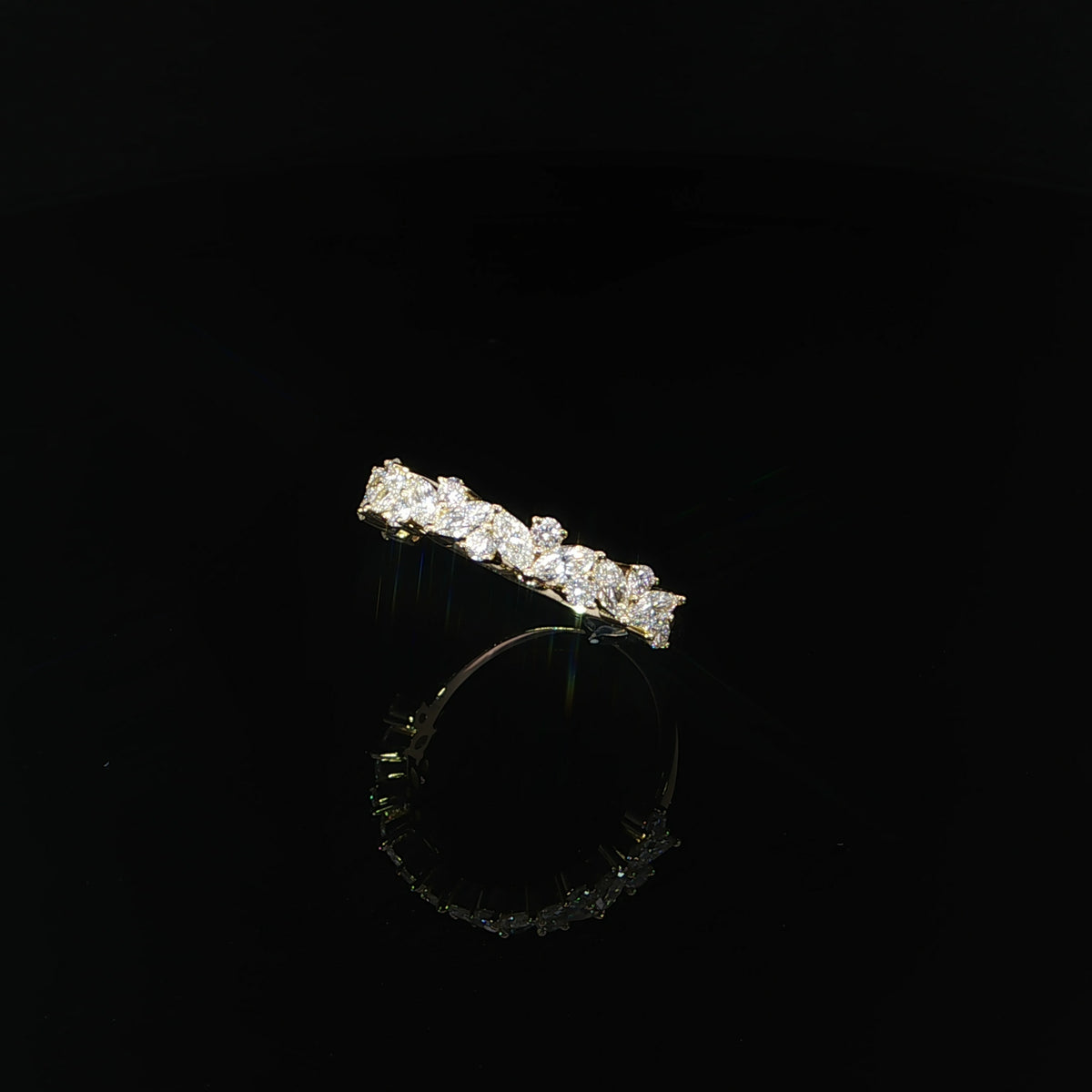 Angled view of a 14K yellow gold multi-shape diamond band with a staggered arrangement of stones.