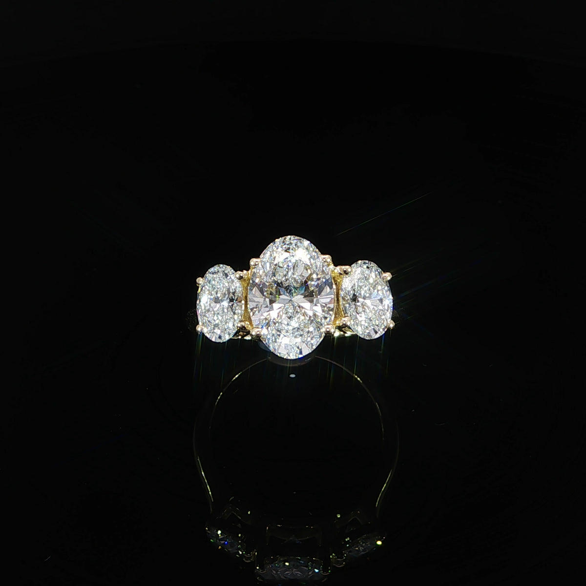 Front view showing a larger oval center flanked by two smaller ovals in yellow gold settings.