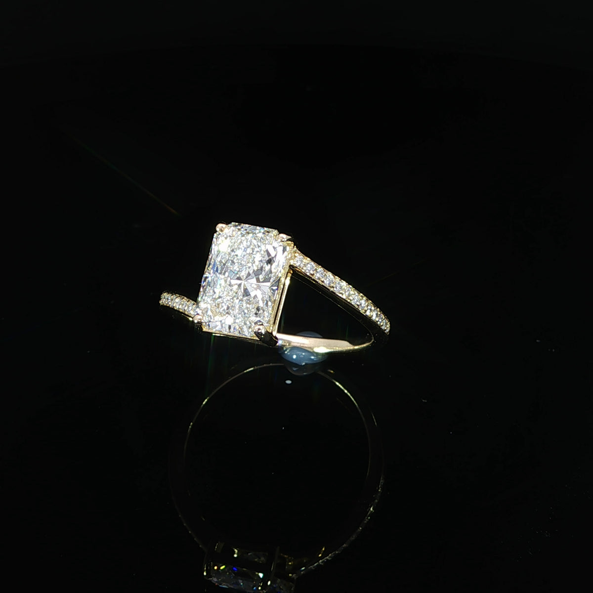 Side angle showing the radiant center setting and diamond accents on the yellow gold band
