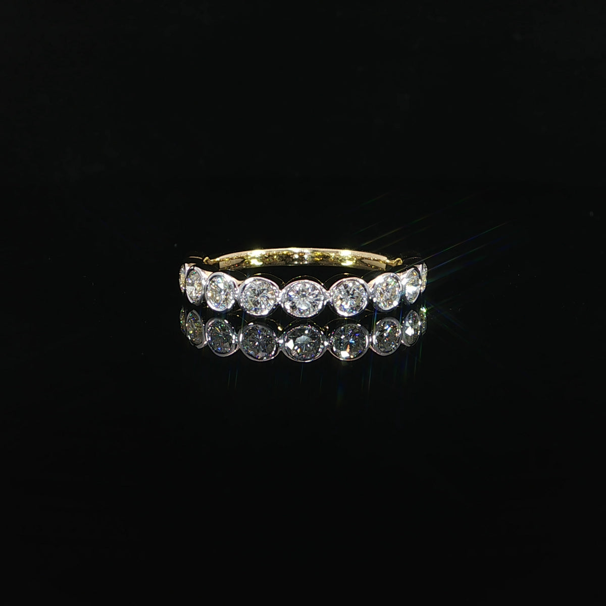 Front view of a 14K yellow gold diamond wedding band with 0.87 CTW D–F color, VS–VVS clarity round lab grown diamonds in elegant bezel settings against a black background.