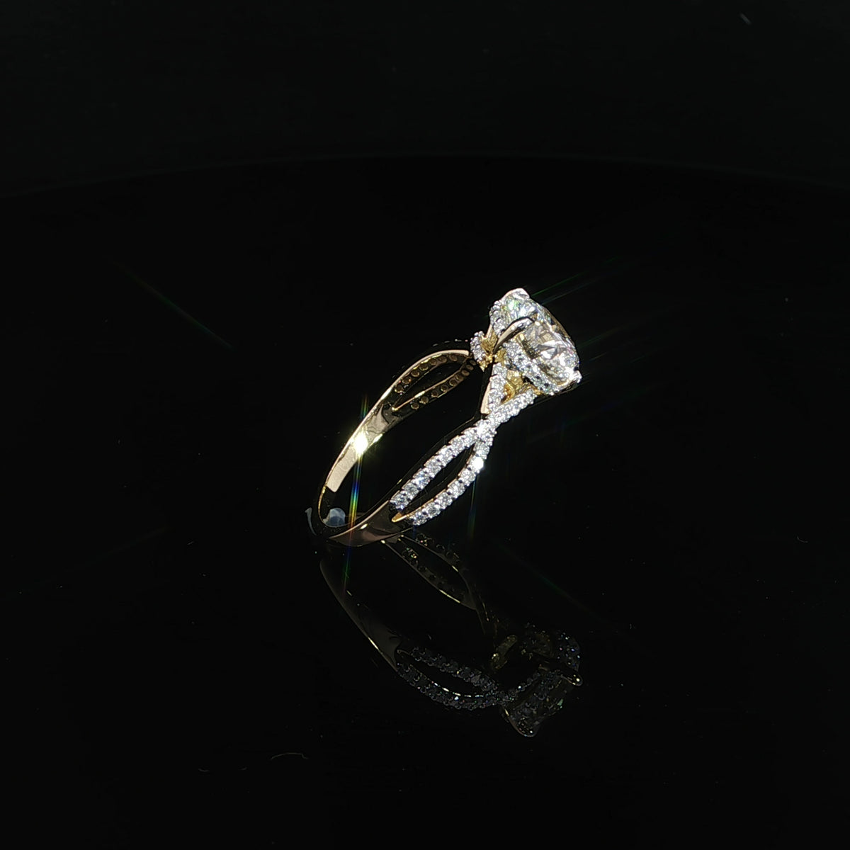 Angled view of a 14K yellow gold ring with a round center diamond and infinity-style twist band.