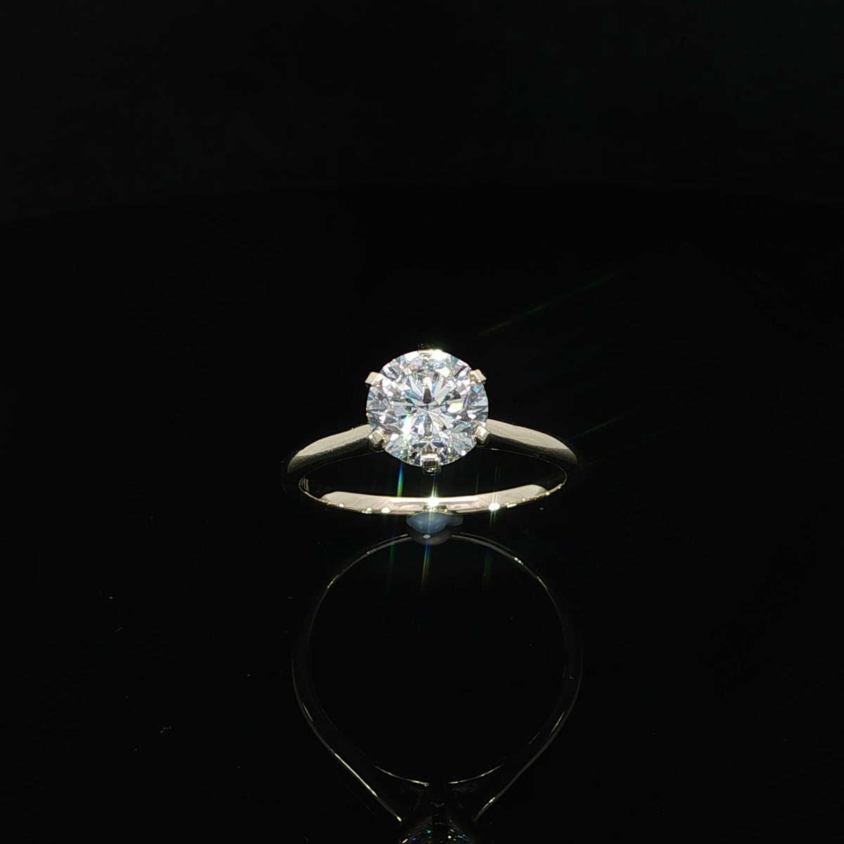 Top view of a round lab-grown diamond held by six yellow gold prongs above a plain band.