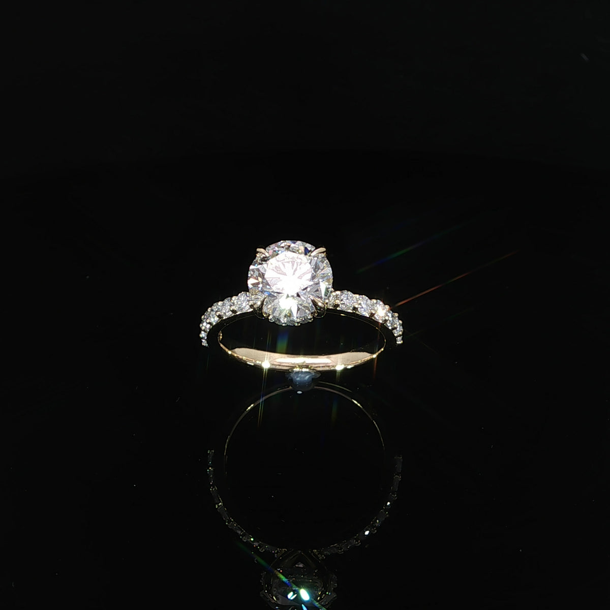 Top view of a yellow gold solitaire-style engagement ring with a round center diamond and diamond-accented band.