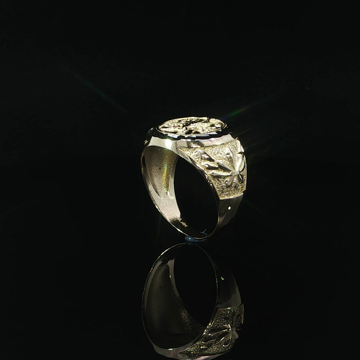 Side view of a 14K yellow gold signet ring with a raised leaf motif, textured shoulder and tapered polished band.