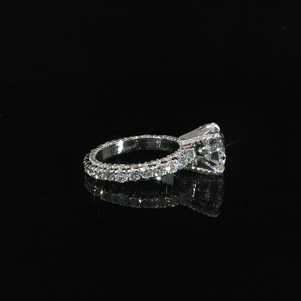 Side profile showing the raised center setting and diamonds around the entire band