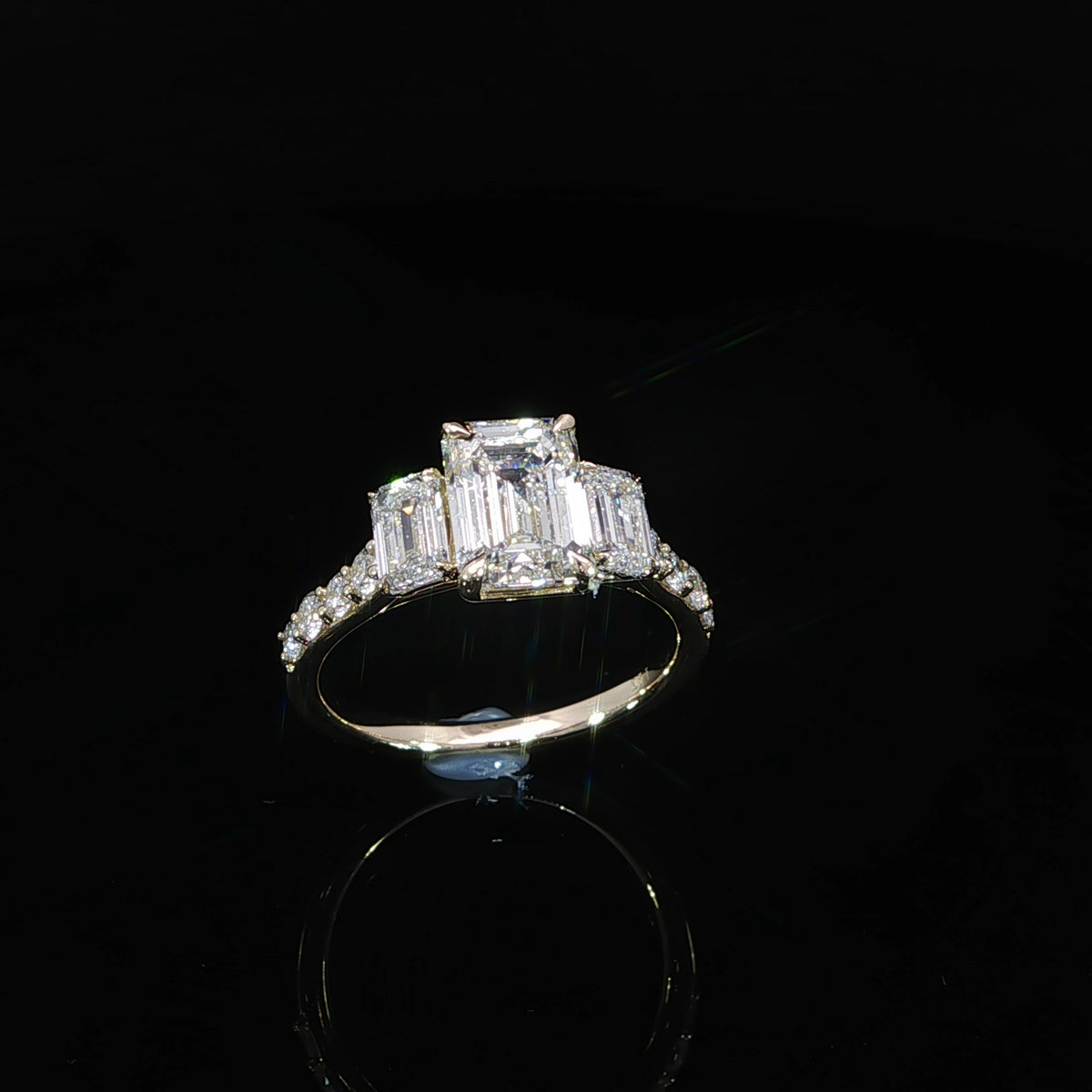 14K yellow gold three-stone engagement ring with a 2.06 carat emerald cut lab grown center diamond and side diamonds.