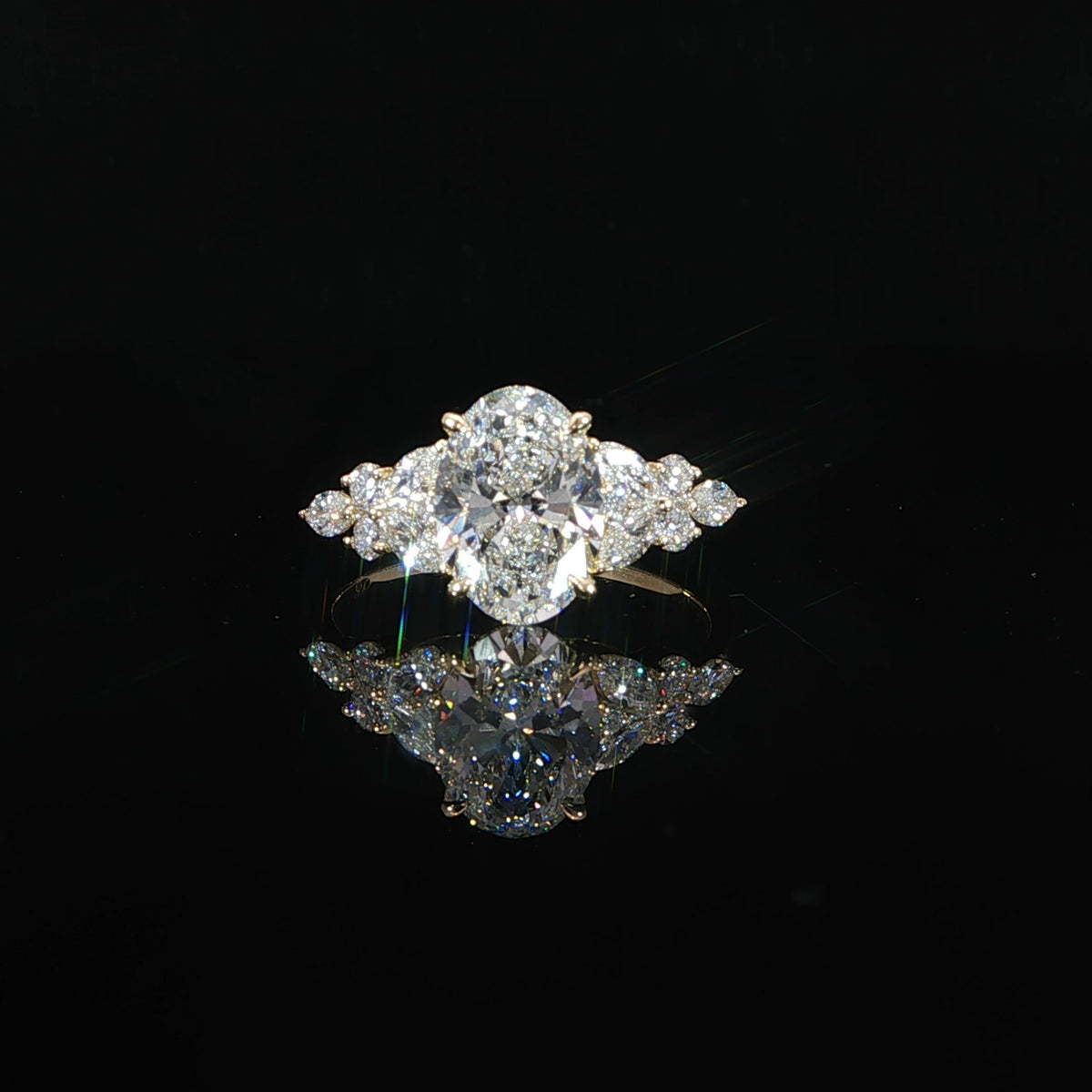 Front view of a 2 carat oval lab grown diamond engagement ring in 14K yellow gold with marquise and round diamond side accents.