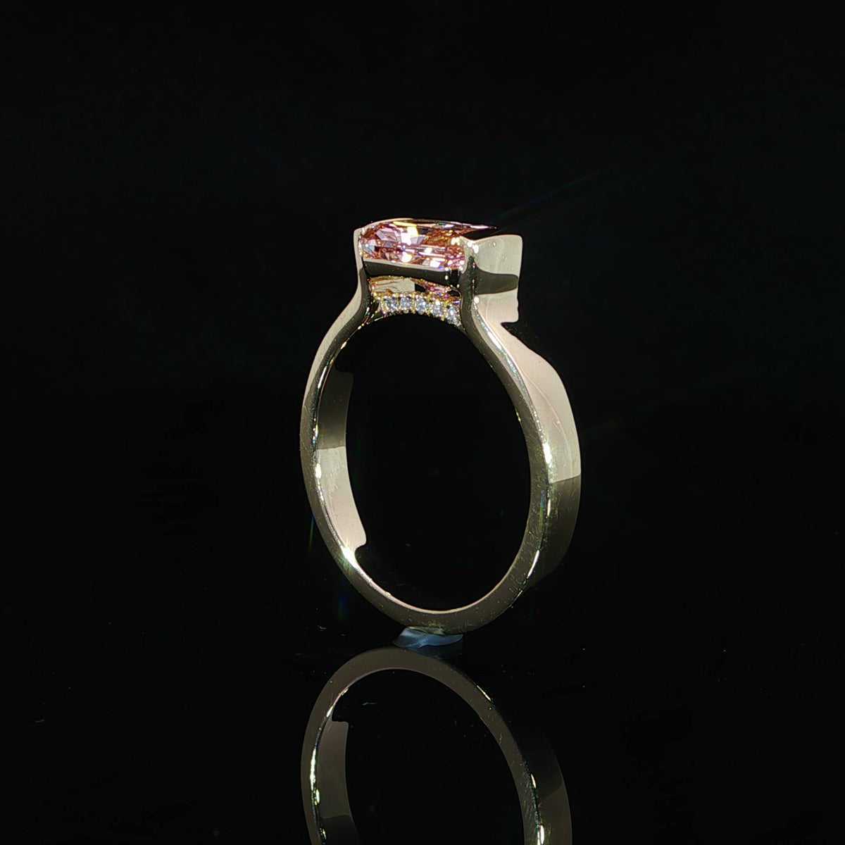 Profile view of a 2 carat pink radiant diamond engagement ring in polished 14K yellow gold.