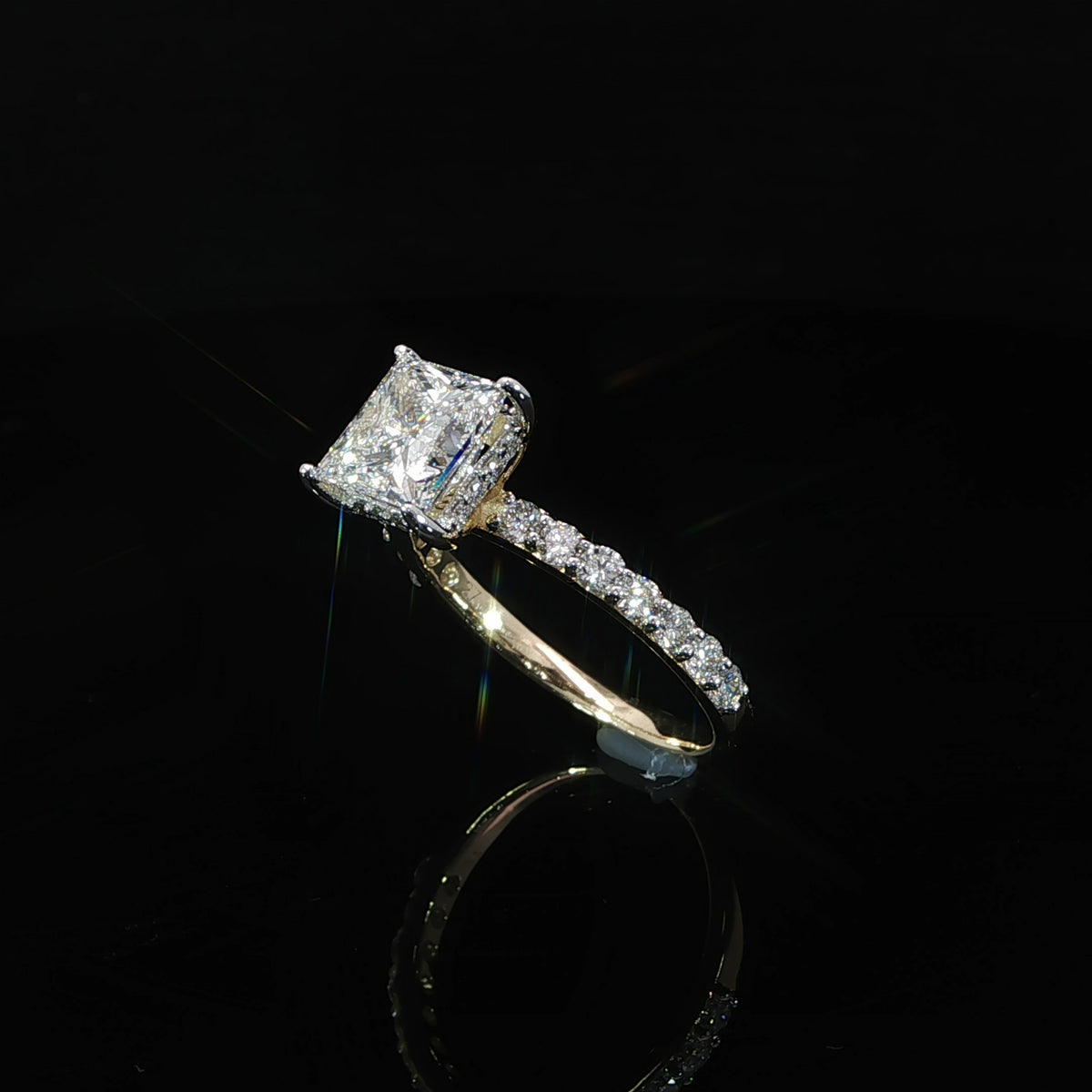 Angled view of a 2 carat princess cut diamond engagement ring with pavé-set shoulders.