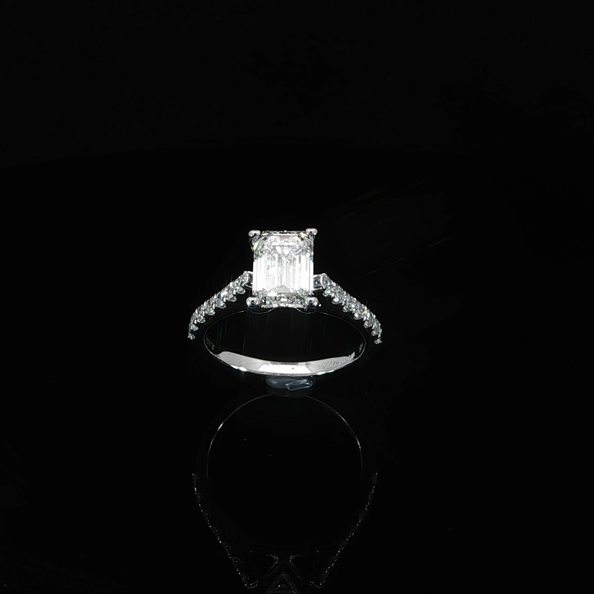 Angled view of a 2.08 carat emerald cut diamond engagement ring with a cathedral setting and diamond accents.