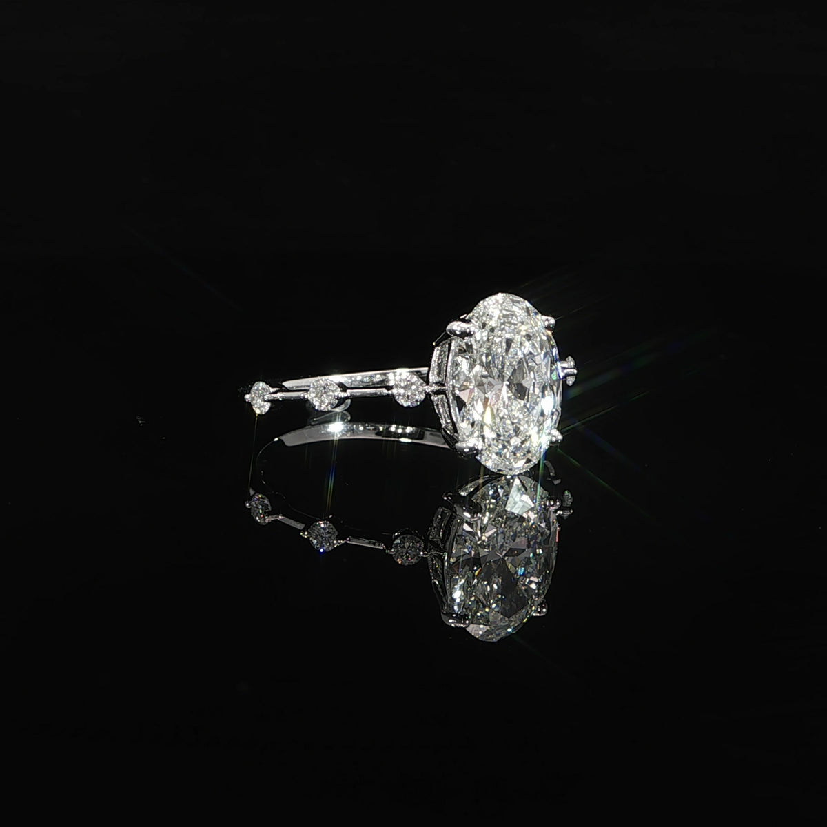 Delicate oval diamond engagement ring with station-set accent diamonds along the band.