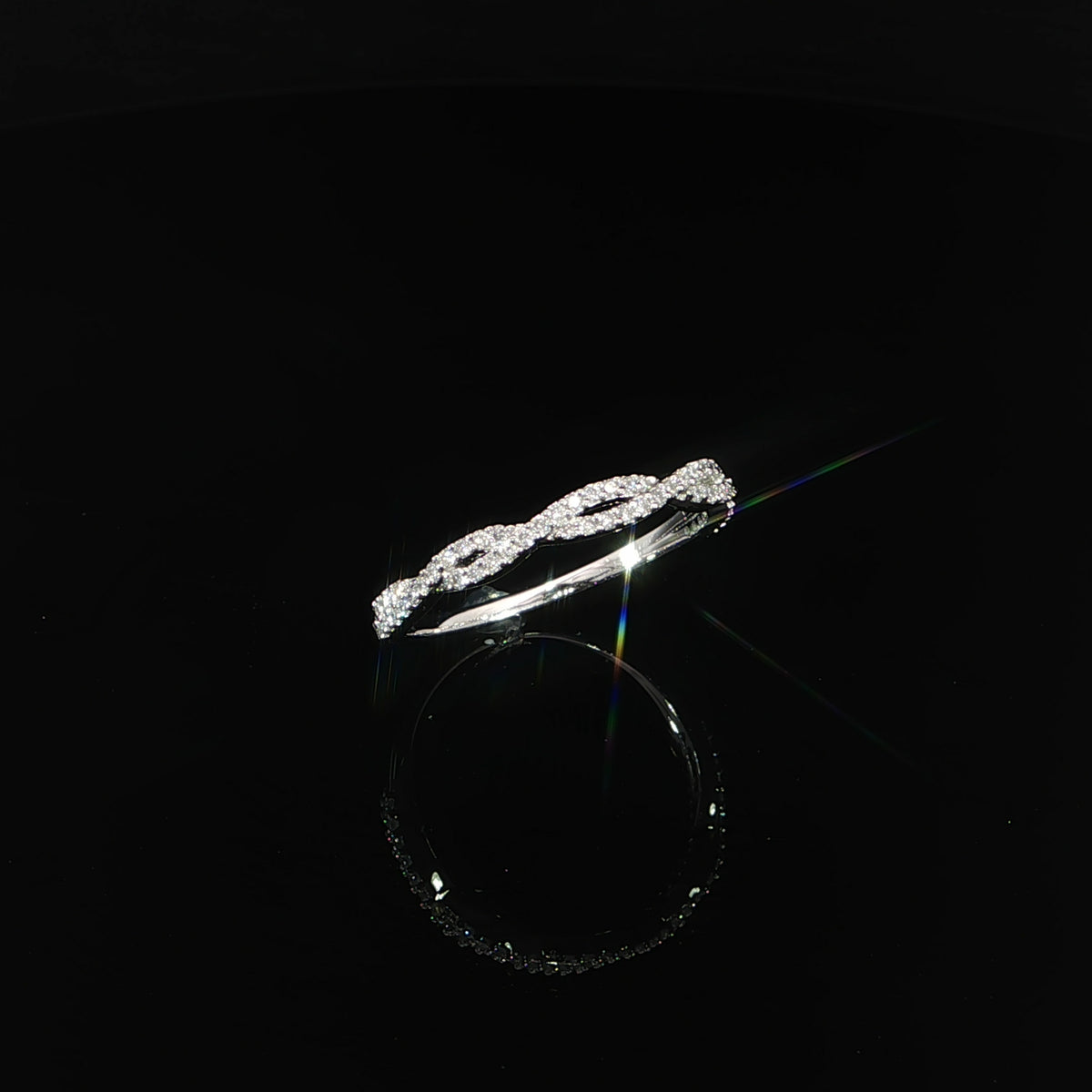 Tilted view of a lab-grown diamond twist band with open loops above a smooth white gold shank.