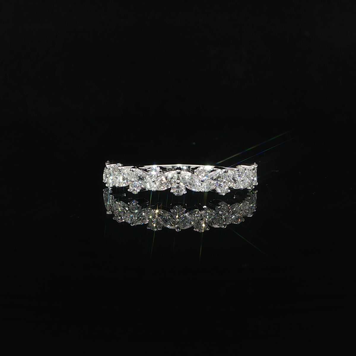 Front view of a lab-grown marquise and round diamond band with its reflection on a black surface.