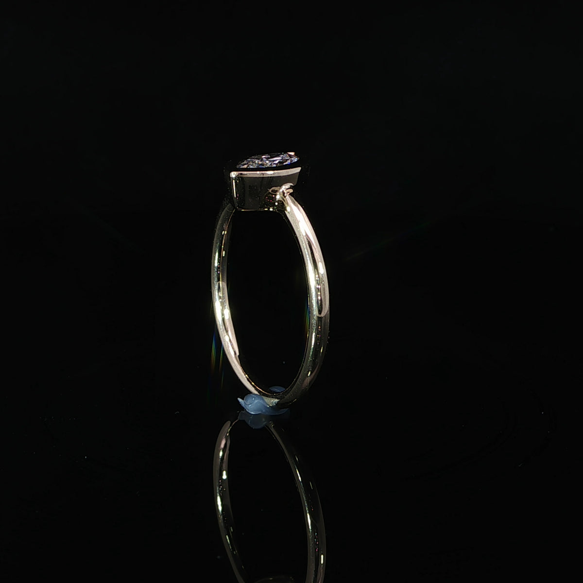 Side view of a marquise bezel set diamond ring showing the low-profile setting and slim yellow gold band.