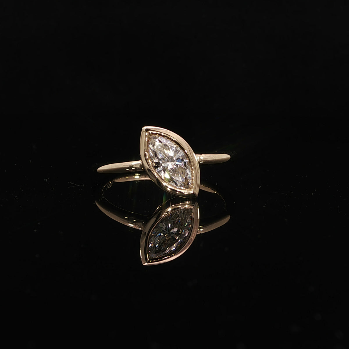 Minimalist 14K yellow gold engagement ring with a bezel set marquise lab grown diamond.