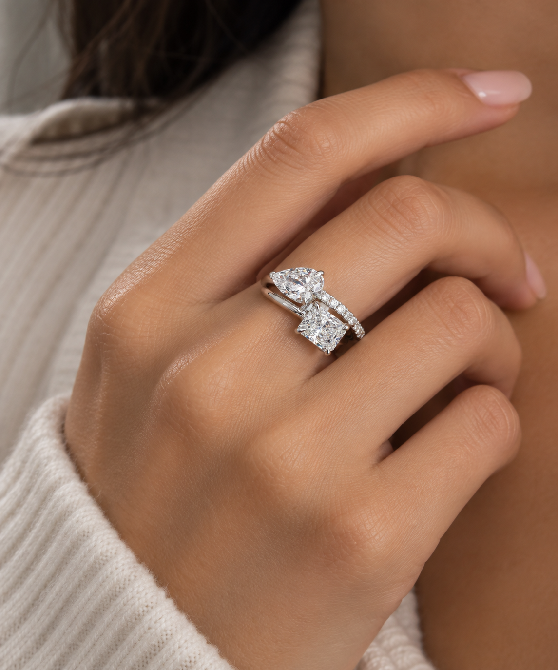 Model wearing Toi et Moi engagement ring with an asymmetrical radiant and pear diamond setting in 14K white gold.