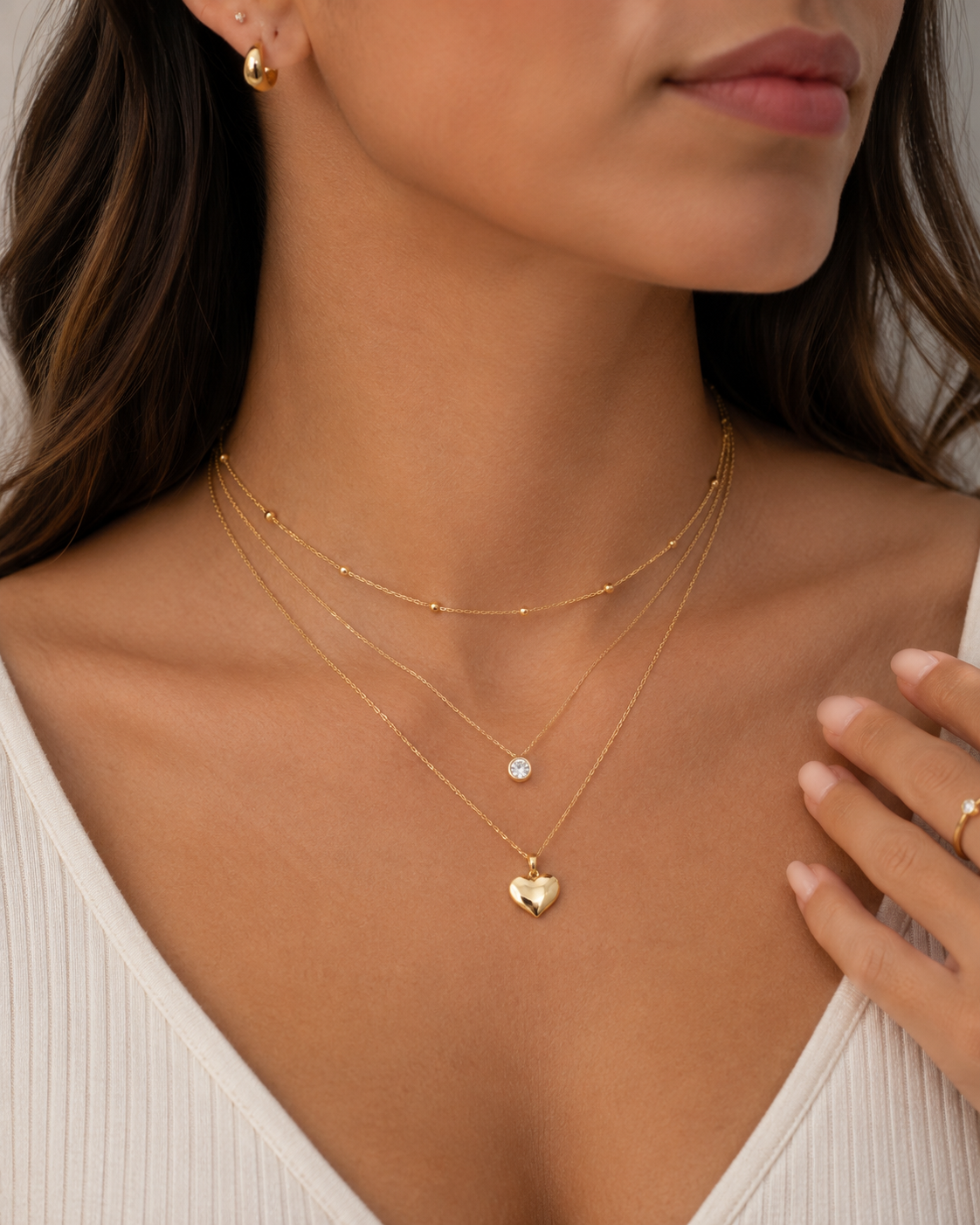 Elegant 3D heart pendant in 14K gold shown layered with other gold, dainty necklaces.