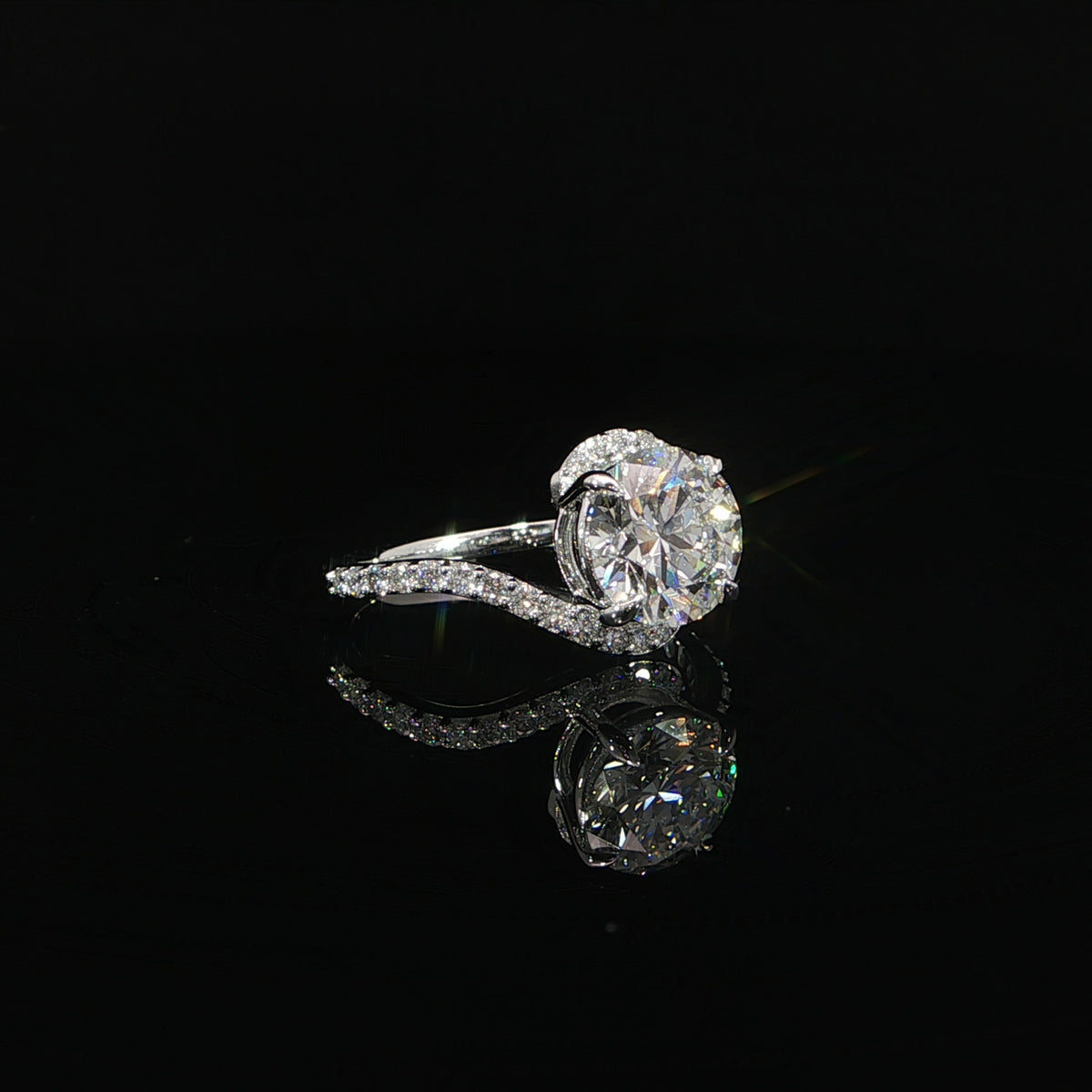 Modern round diamond engagement ring with a flowing asymmetrical bypass design in white gold.