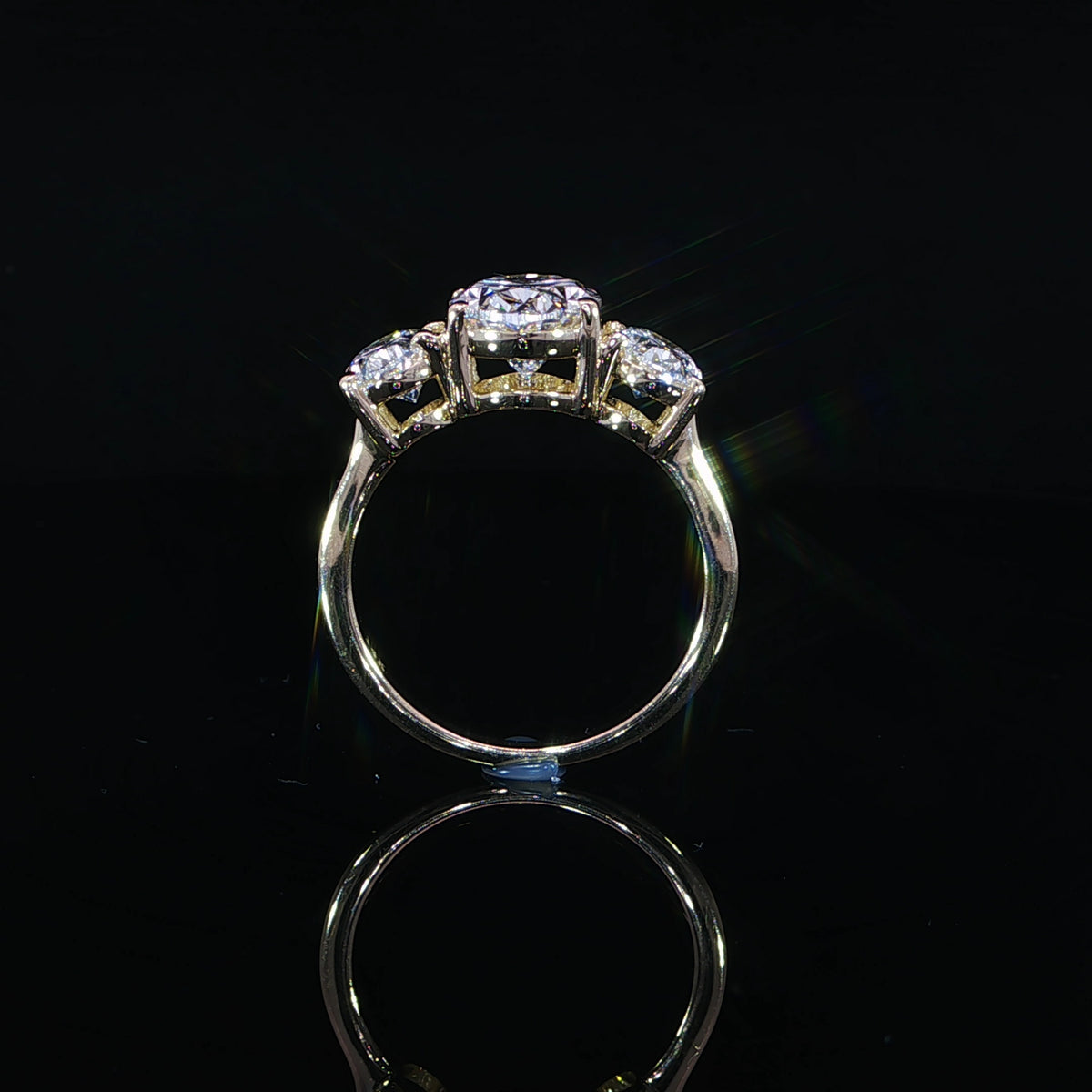 Yellow gold diamond ring positioned upright showing the open gallery on a reflective black surface.