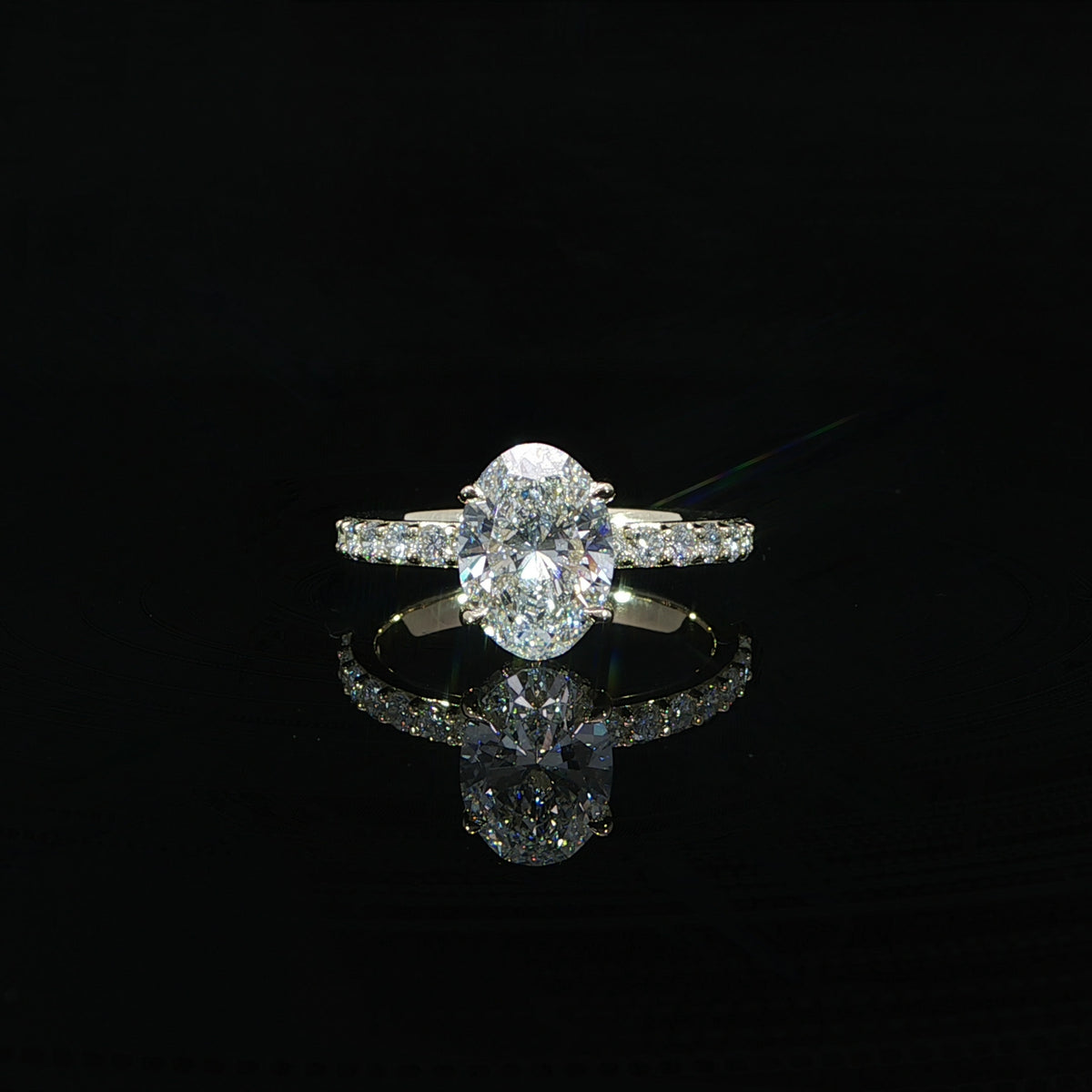 Front view of an oval diamond engagement ring featuring a four-prong setting and sparkling diamond band.