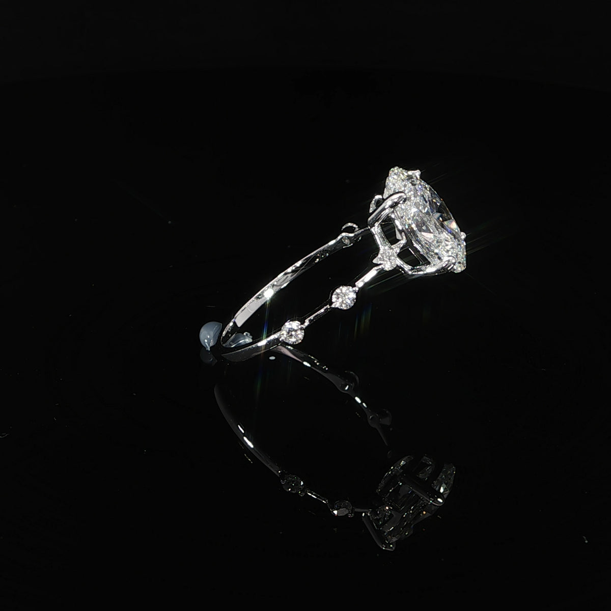 Angled view of an oval engagement ring with a slender diamond station band in 14K gold.