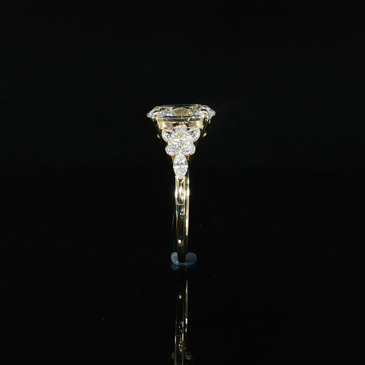 Side profile of a 14K yellow gold oval lab grown diamond engagement ring showing the raised center setting and accent stones.