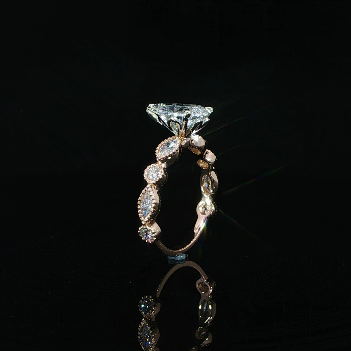 Pear diamond engagement ring with bezel set marquise and round diamond accents in rose gold.