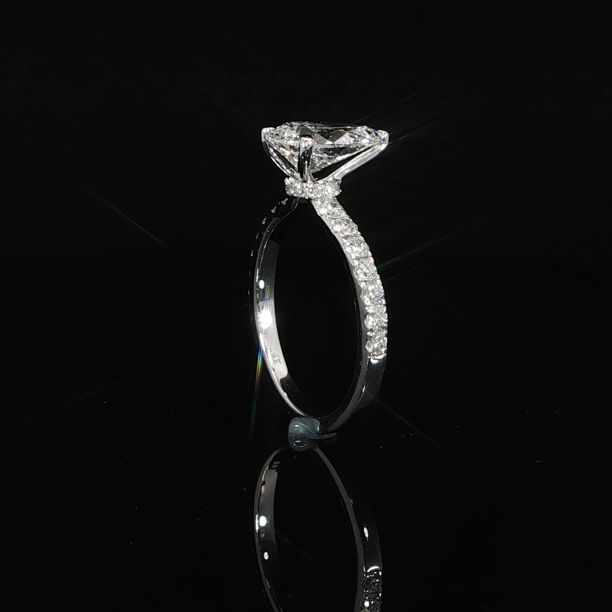 Small diamonds beneath the raised pear setting form the ring’s hidden halo.