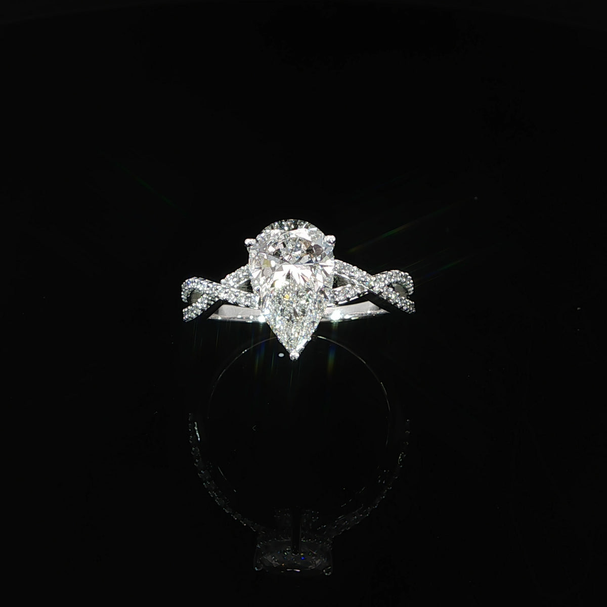 Top view of a pear-shaped diamond engagement ring with an intertwined diamond twist band.