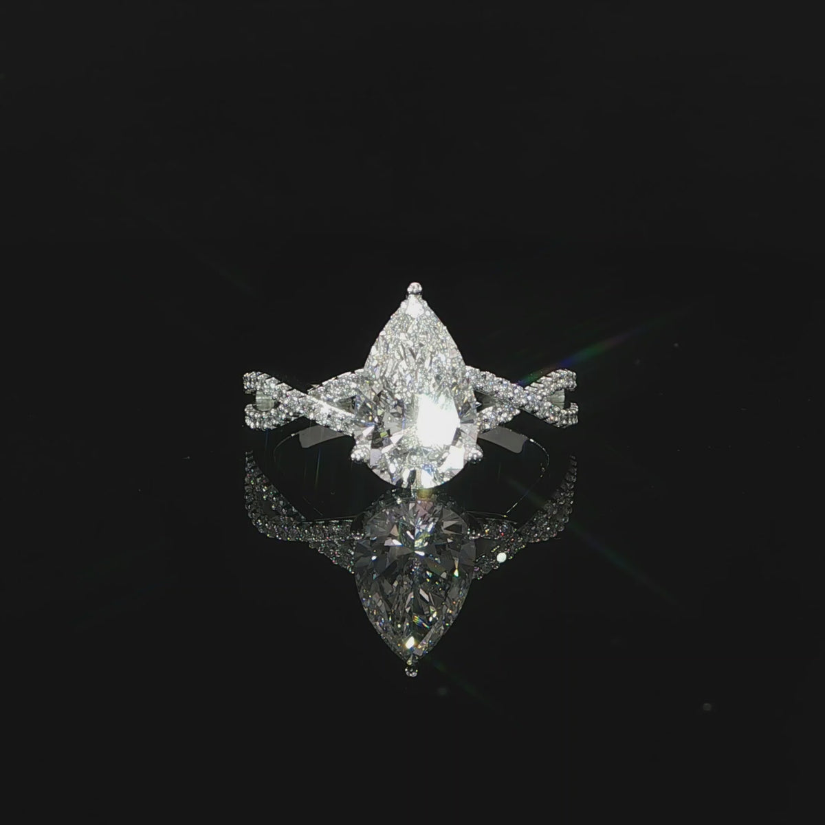 Modern pear-shaped diamond engagement ring with a flowing twist band and hidden halo.