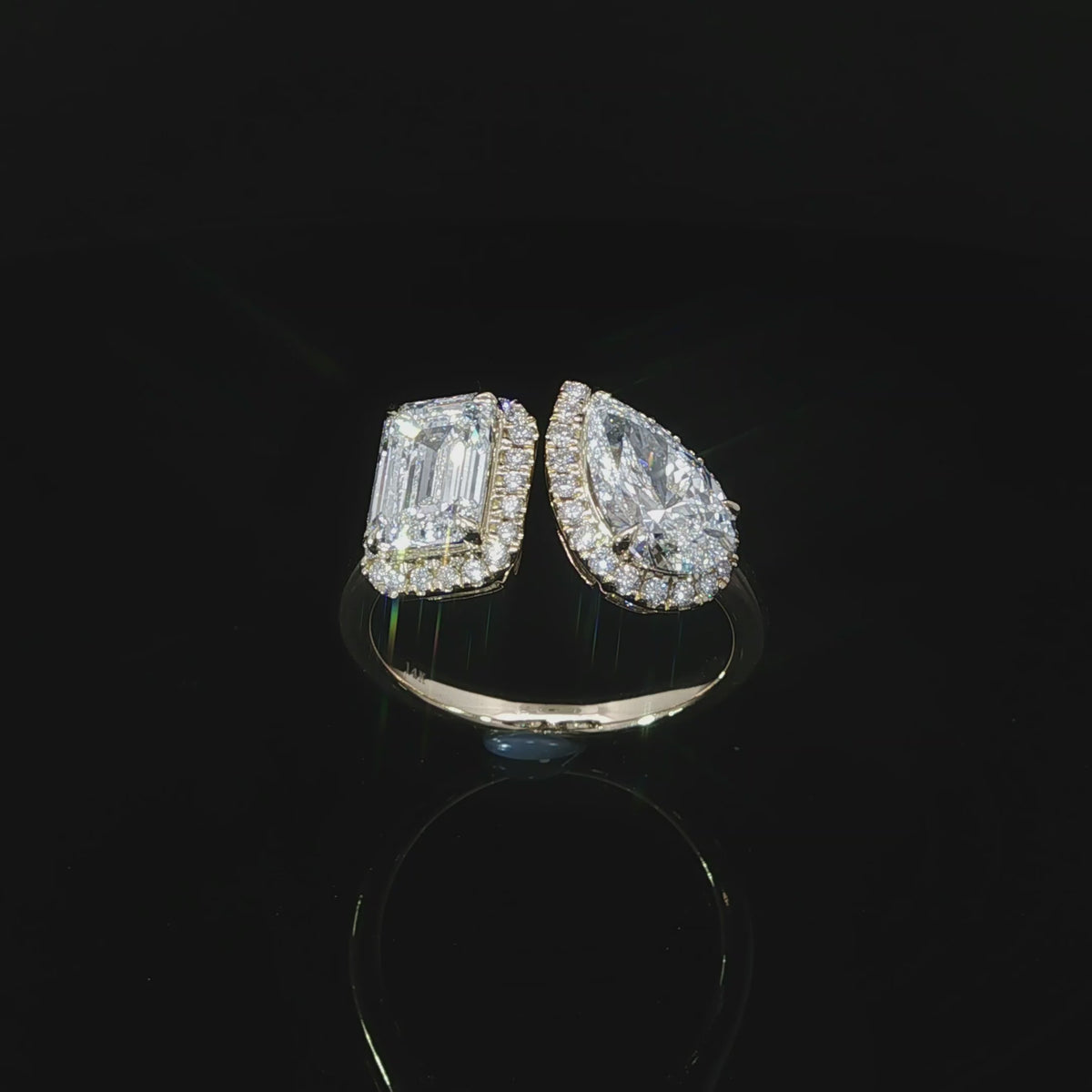 Yellow gold diamond ring with emerald and pear shaped center stones accented by halo diamonds