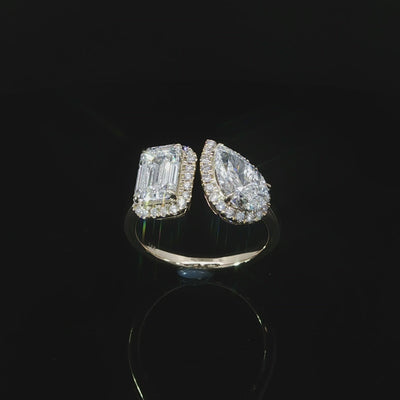 Yellow gold diamond ring with emerald and pear shaped center stones accented by halo diamonds