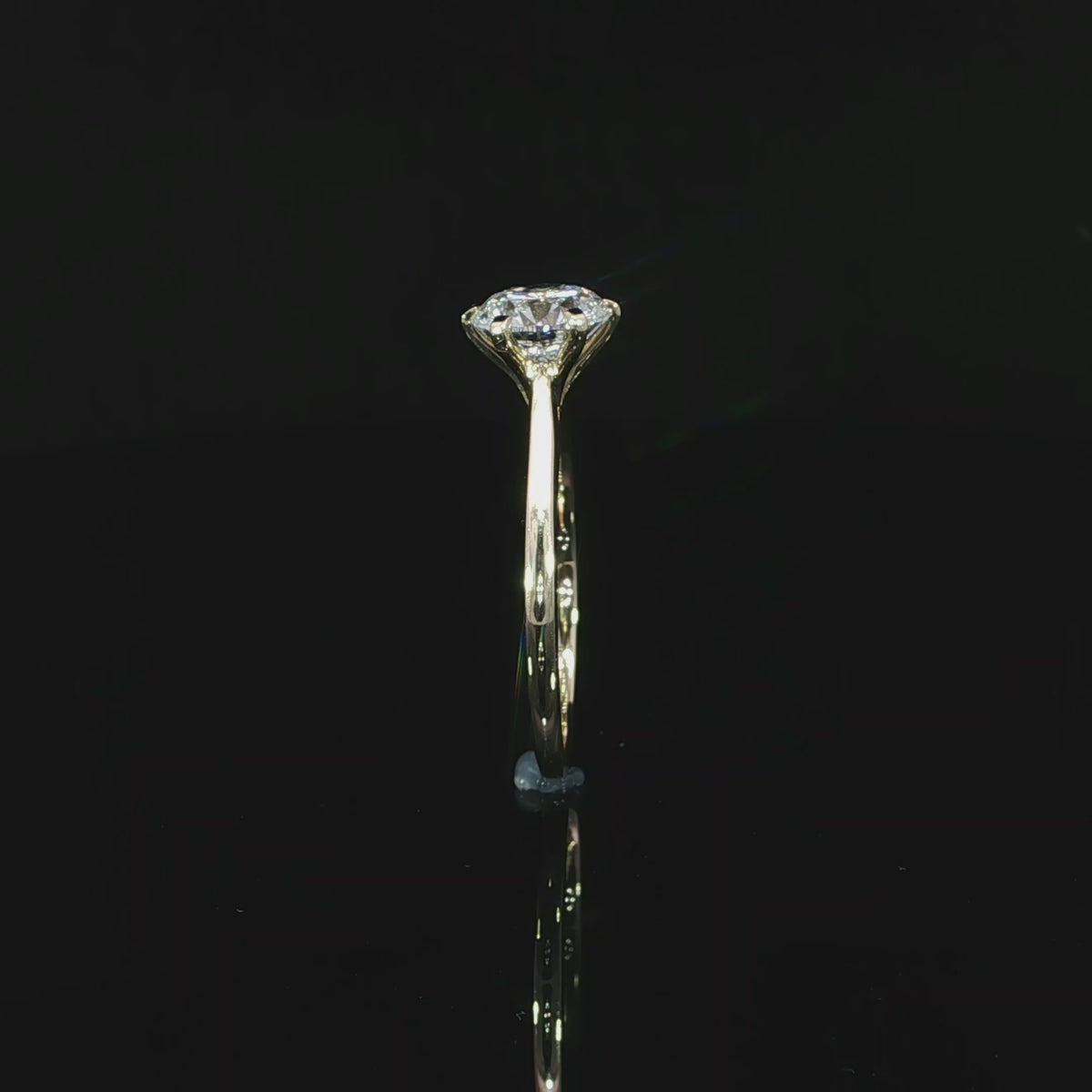 Standing 14k yellow gold solitaire and its mirrored reflection on a black surface 360 video.