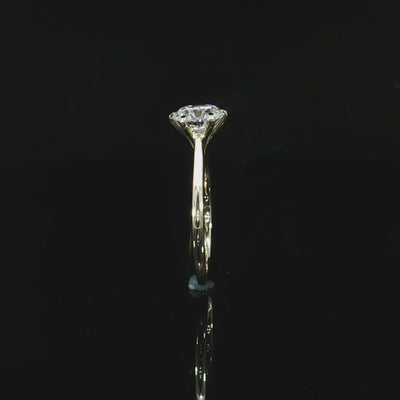Standing 14k yellow gold solitaire and its mirrored reflection on a black surface 360 video.