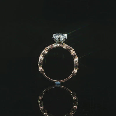 Detailed view of a pear cut diamond ring with decorative bezel set side diamonds along the band.