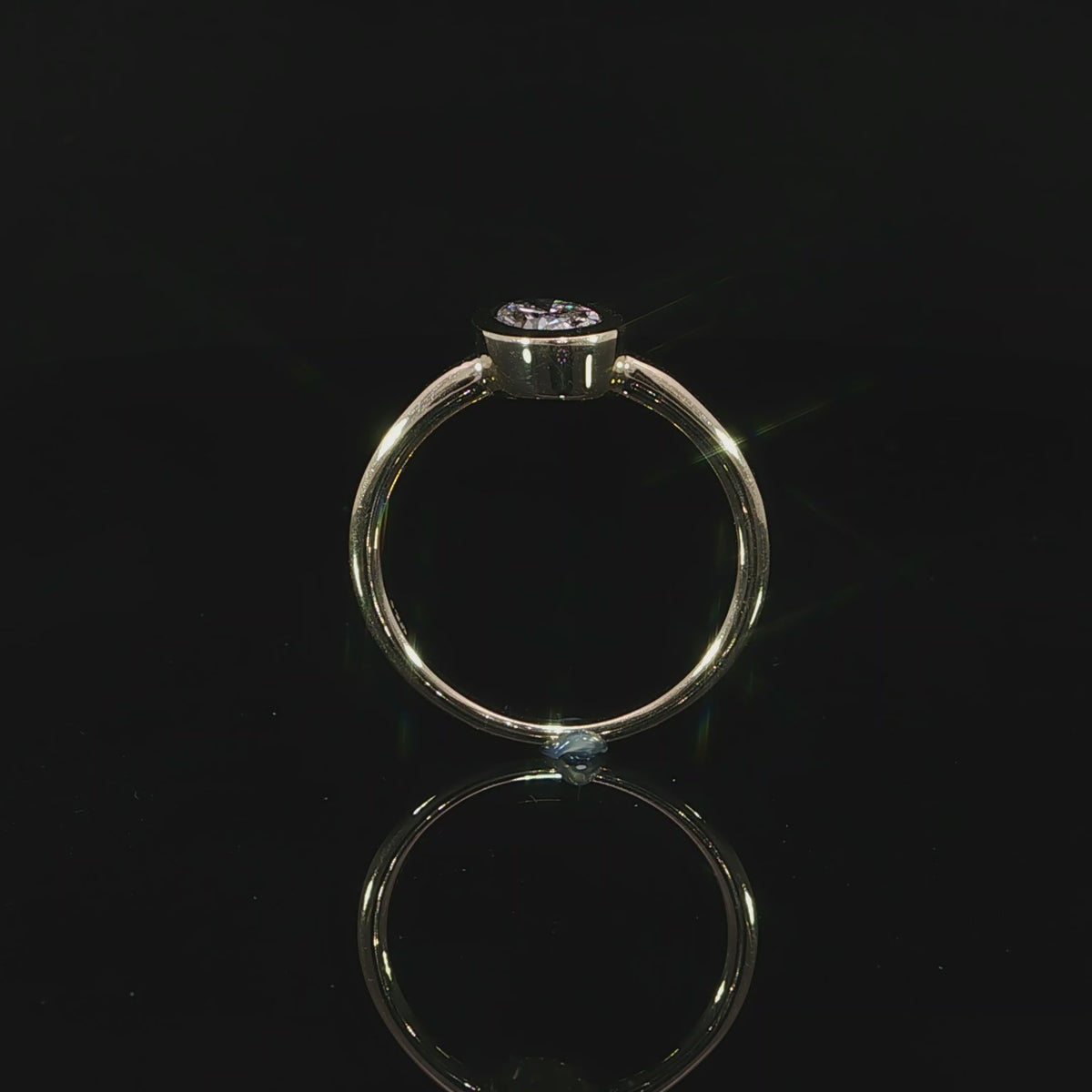 Minimalist 14K yellow gold engagement ring with a bezel set oval lab grown diamond.
