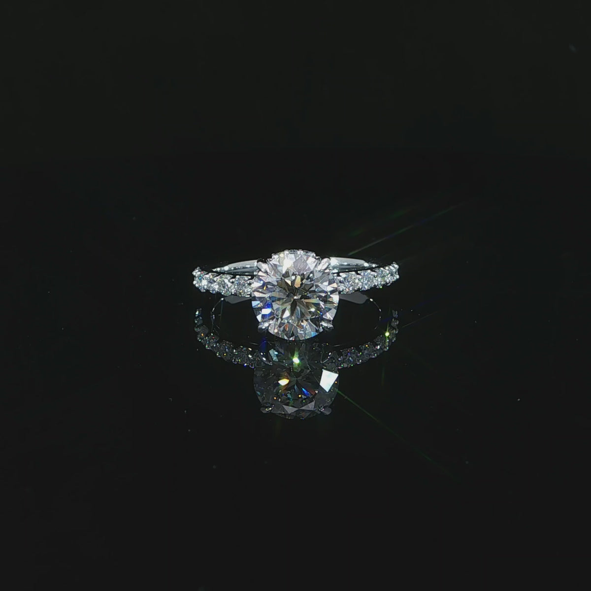 Modern round solitaire-style engagement ring with a hidden halo and diamond-accented white gold band.
